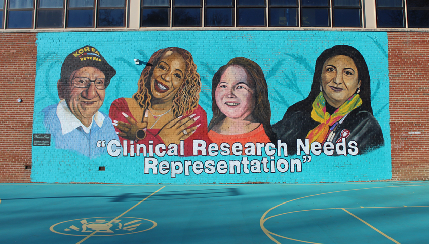 Photo of large teal mural painted on brick wall of school building, featuring four people from under-represented communities