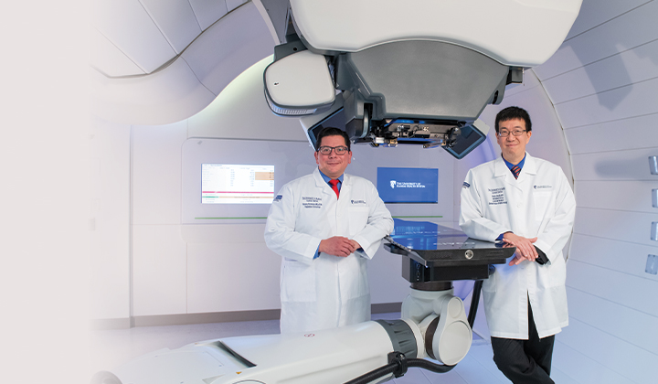 Dr. Rotondo (left) and Dr. Chen (right) standing with Proton Therapy machine.