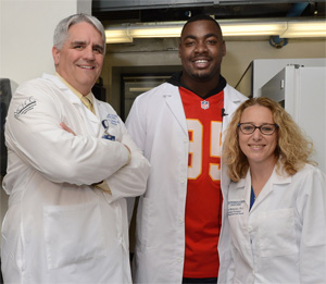 Dr. Roy Jensen, Director of The University of Kansas Cancer Center, Kansas City Chiefs' Chris Jones and researcher Mary Markiewicz, Ph.D.