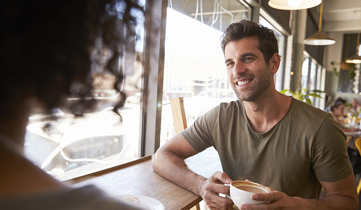 Man smiling and holding coffee.