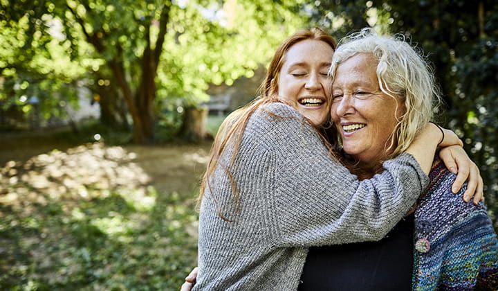 Mother and daughter embracing outside on a sunny day