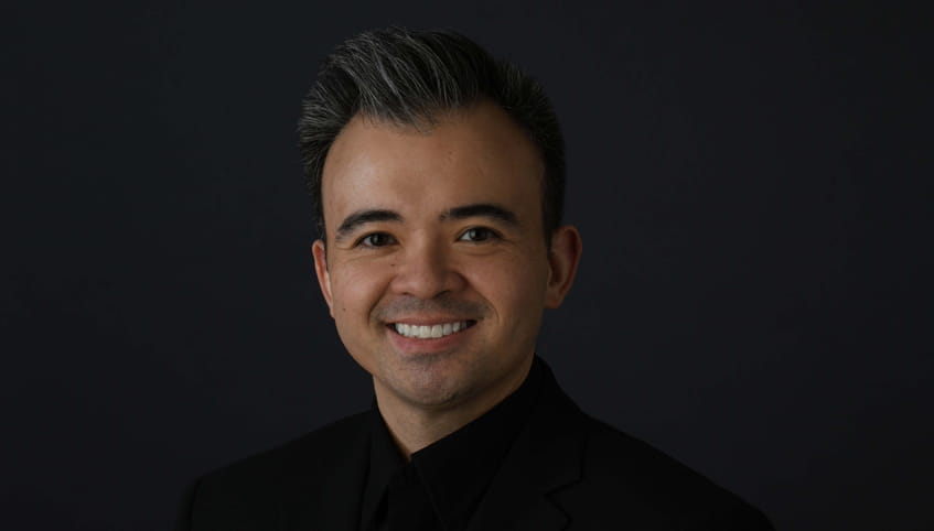 Dr. Rodriguez wears black and stands in front of a black background