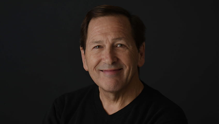 Dr. Weitzel wears black and stands in front of a black background