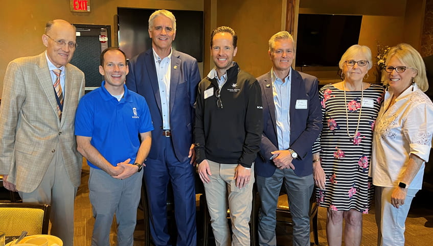 Group of individuals stand together smiling at community celebration