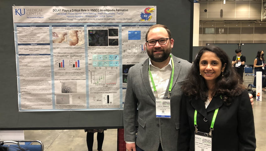 A man and a woman stand in front of a scientific poster. 
