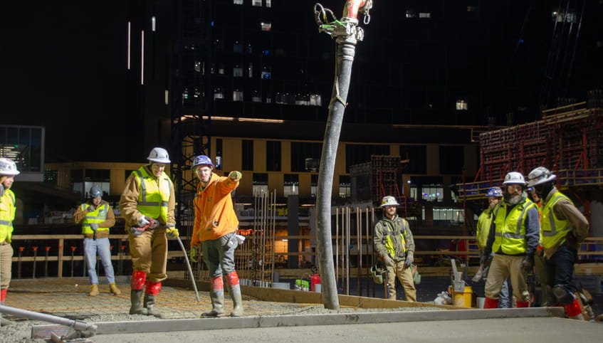 Men in hard hats and reflective jackets work at a construction site