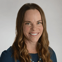professional headshot of a smiling person with brown shoulder-length hair