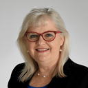 professional headshot of a smiling person wearing red glasses and shoulder-length blonde hair