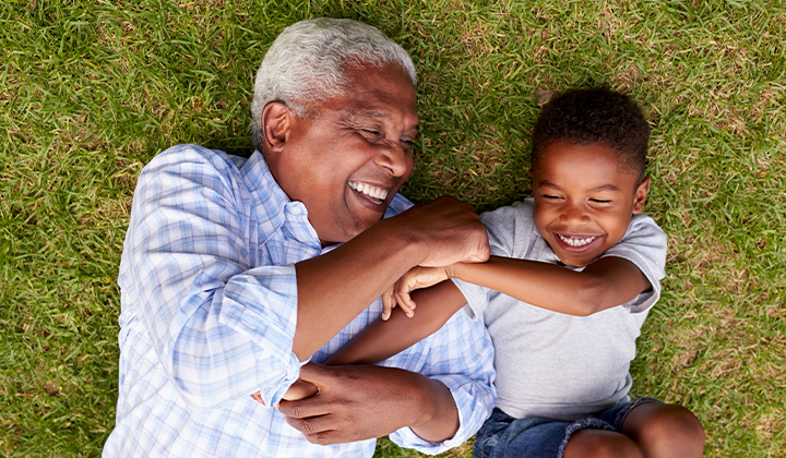 Grandfather and grandson laughing in grass