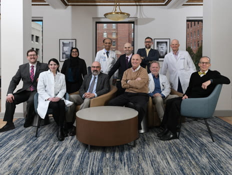 Group of researchers sitting and standing together, some in white lab coats and others in business attire.