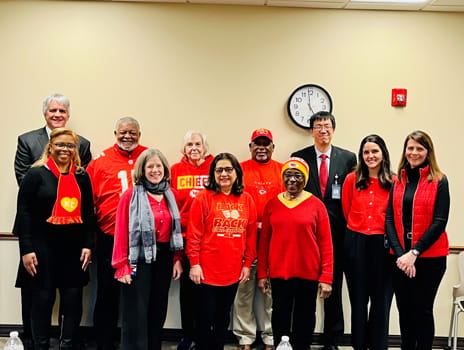 A group of people wearing red stand together smiling.