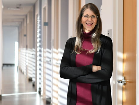 Woman with long dark hair, wearing a black sweater and glasses.