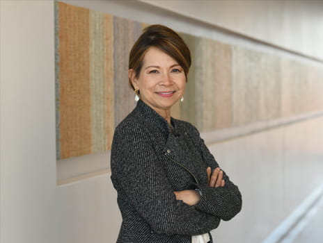 Person with brown hair held back from their face wearing a dark grey jacket smiles toward the camera.