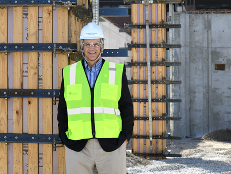 Dr. Roy Jensen wears a construction vest, hard hat and safety goggles while standing in a construction site. 
