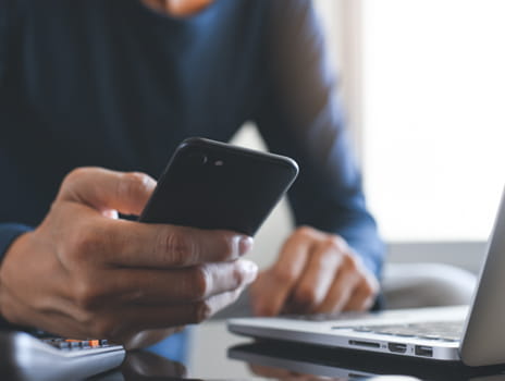Person holding phone while on laptop