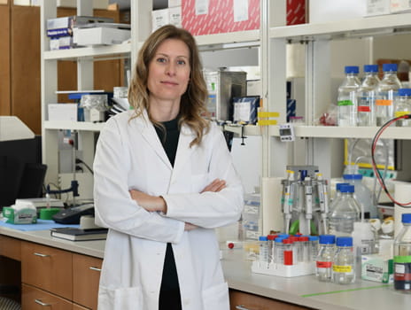 Dr. Kristy Brown stands in front of a laboratory bench wearing a white lab coat