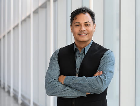 Dr. Simon Lee stands facing the camera smiling with arms crossed across his chest