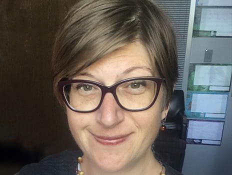 Headshot of individual with short, brown hair and glasses