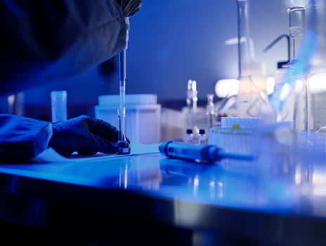Lab countertop filled with various equipment lit by a blue light.