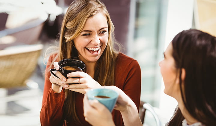 Patient smiling and enjoying coffee after recovering from successful leukemia treatment.